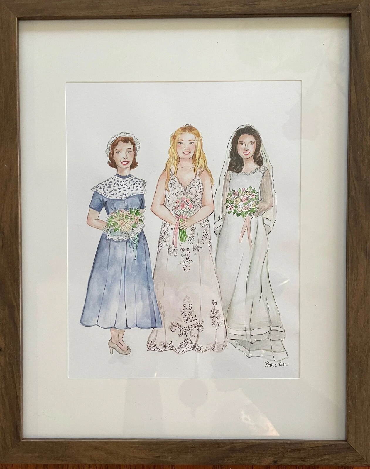 A framed custom watercolor of three generations of brides in their wedding gowns, signed Katie Rose
