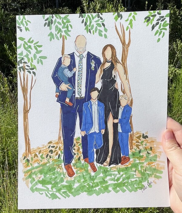 A hand-drawn family portrait held up among the trees where it was painted
