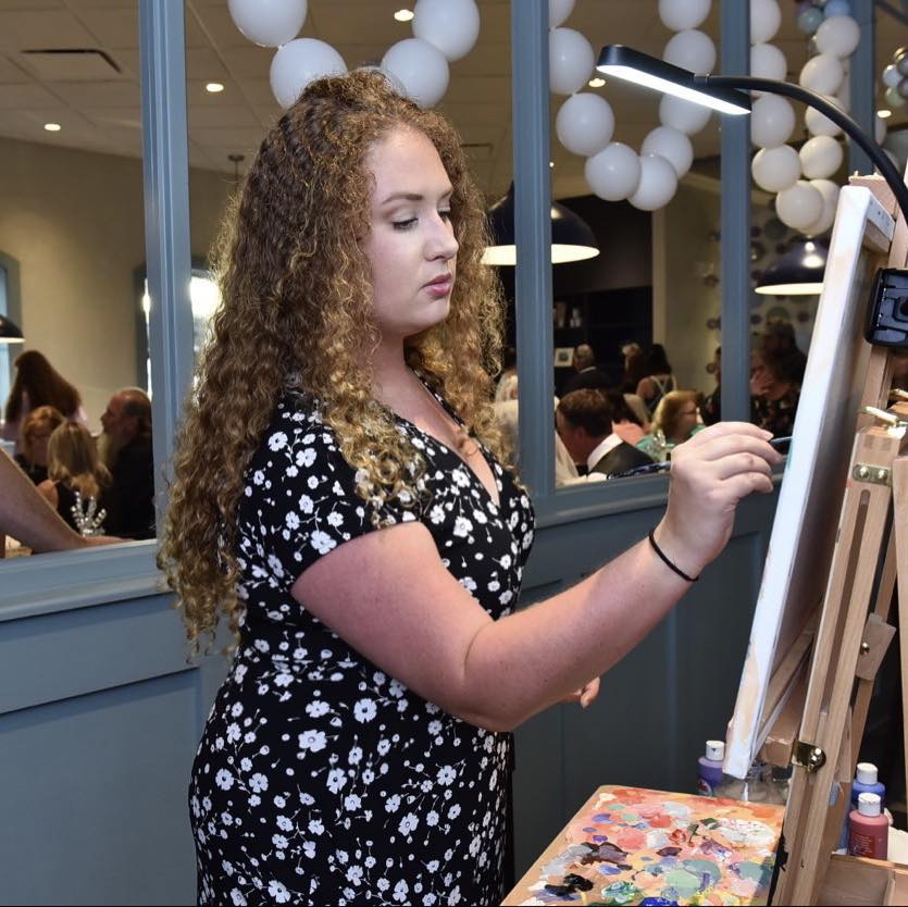 Katie painting live at her easel during an event