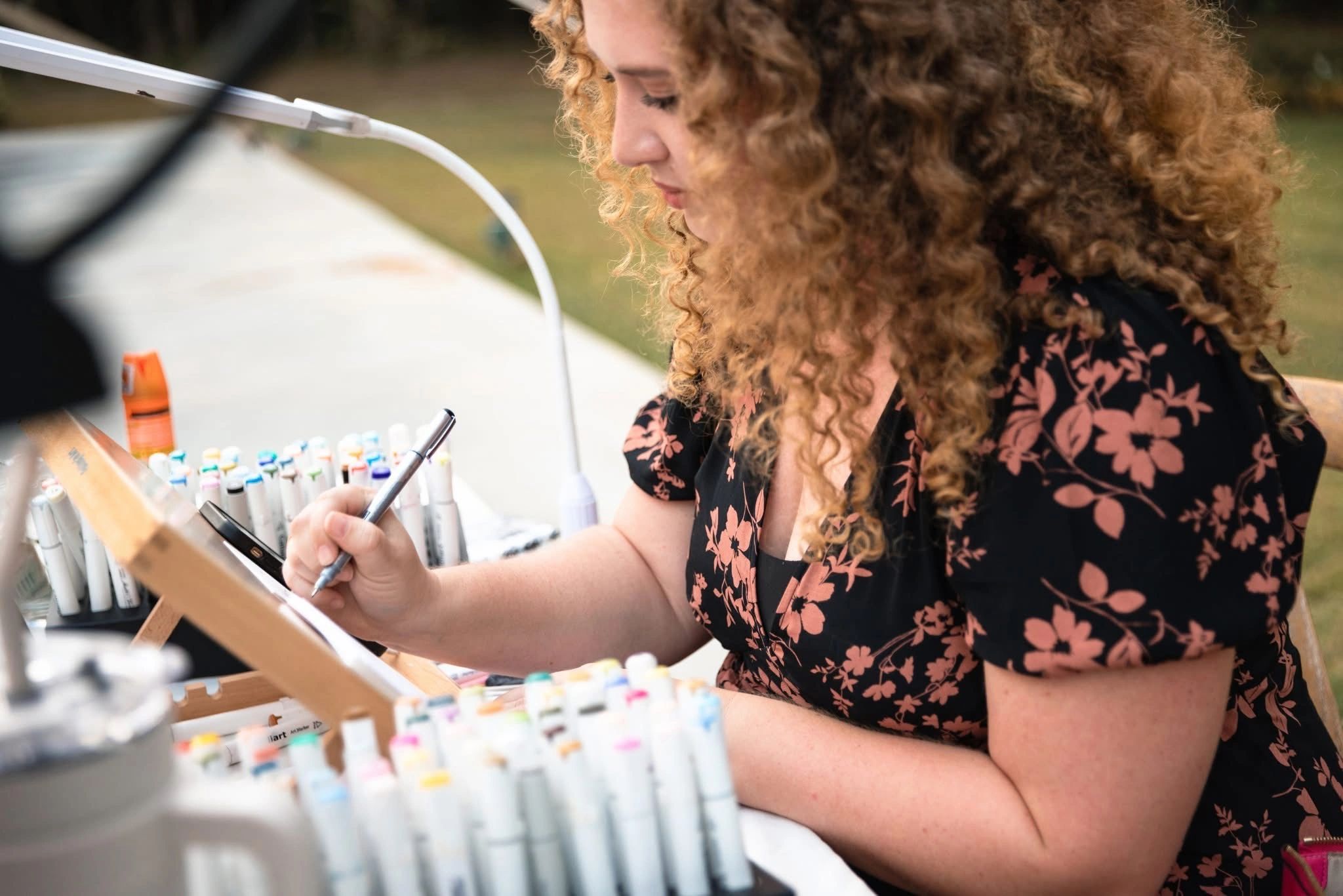 Katie painting live at her easel, markers laid out beside her
