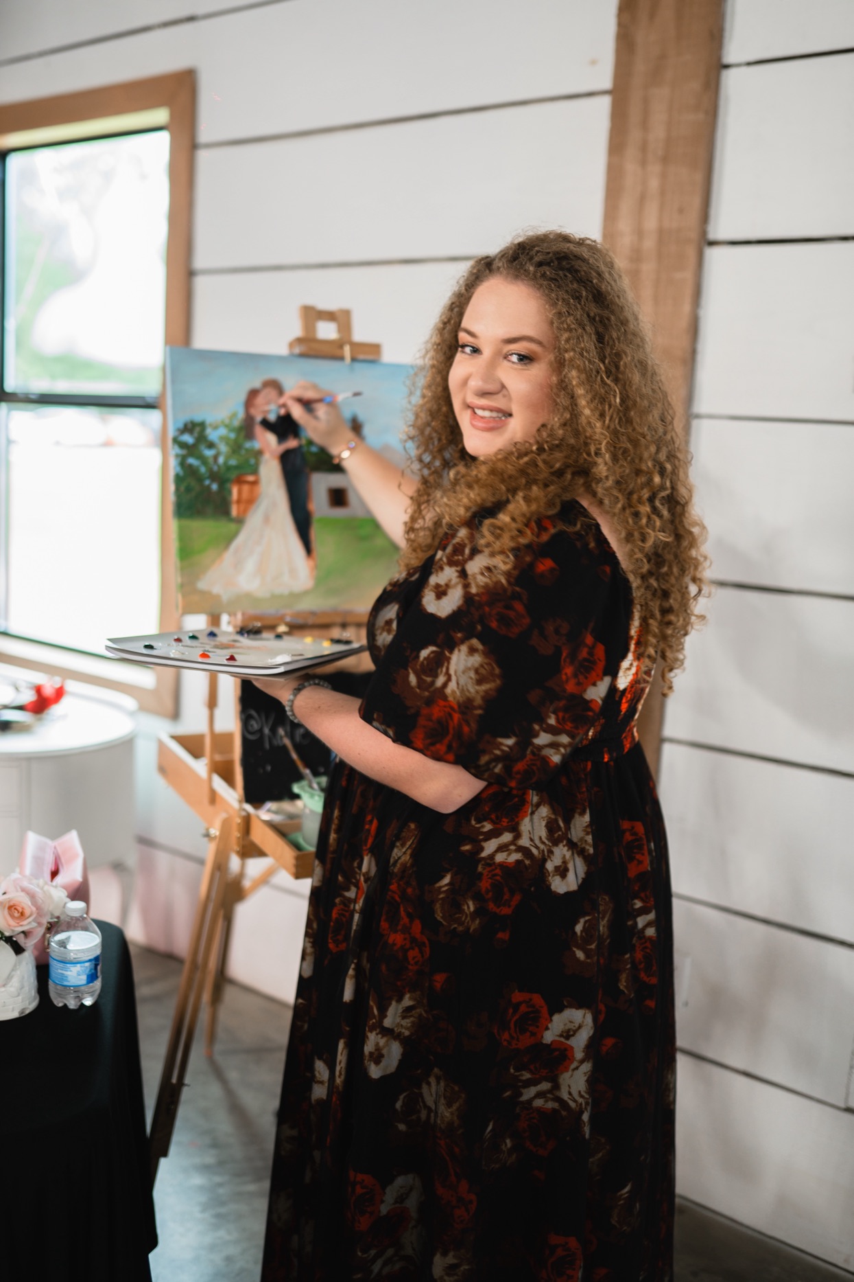 Katie at her easel, live painting a first dance at a wedding