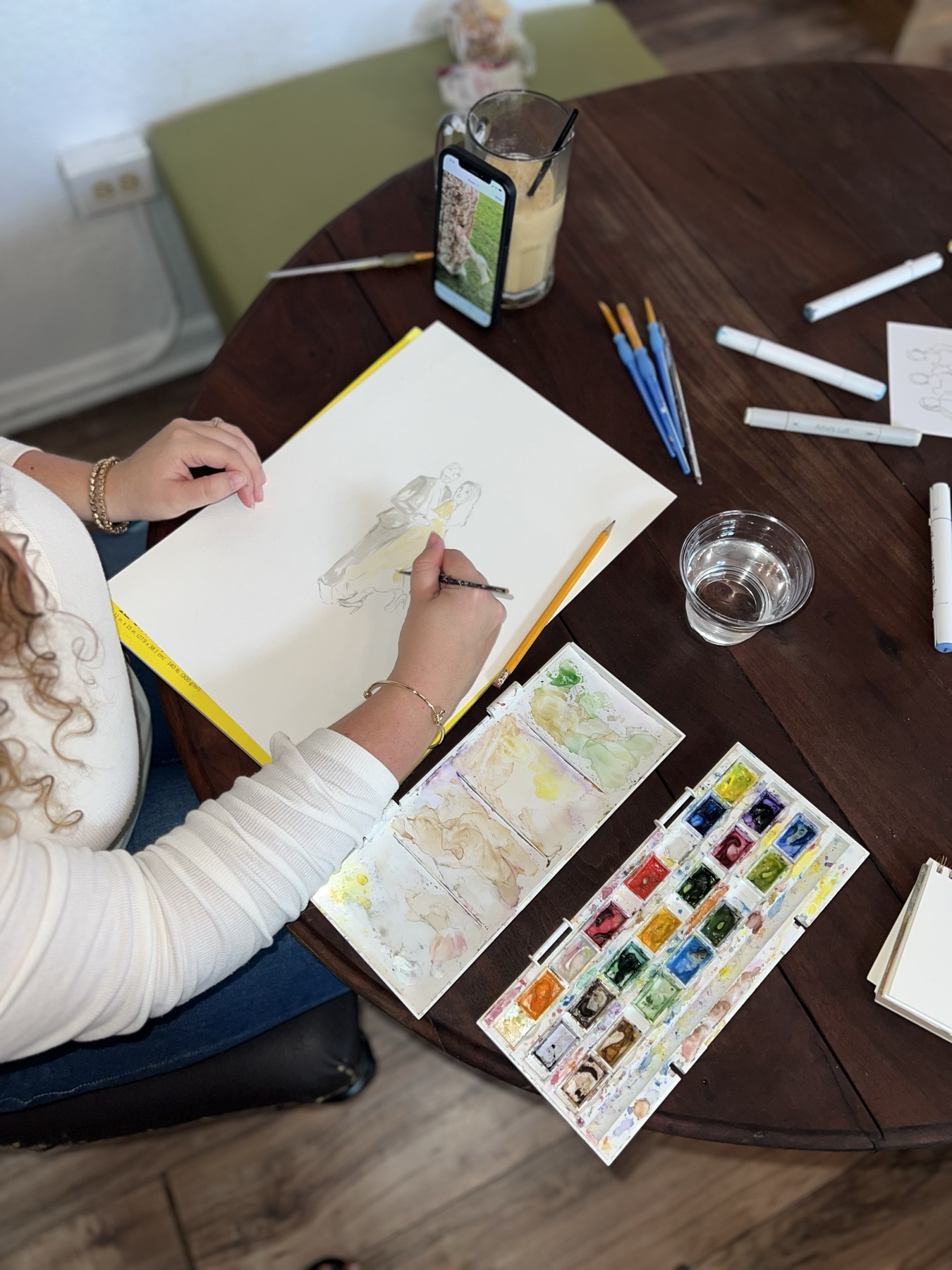 Katie beginning a watercolor sketch of a couple from their photo